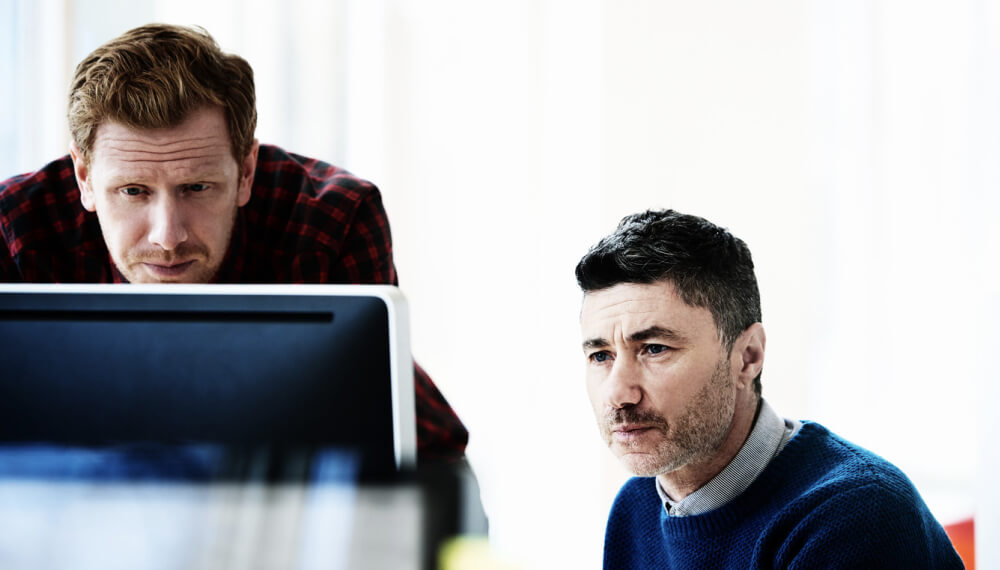 Office colleagues using Infor iPaaS solution on a computer to complete a project